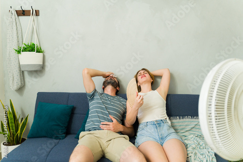 Obraz na płótnie Exhausted couple sweating and suffering from summer heat wave at home w salonie