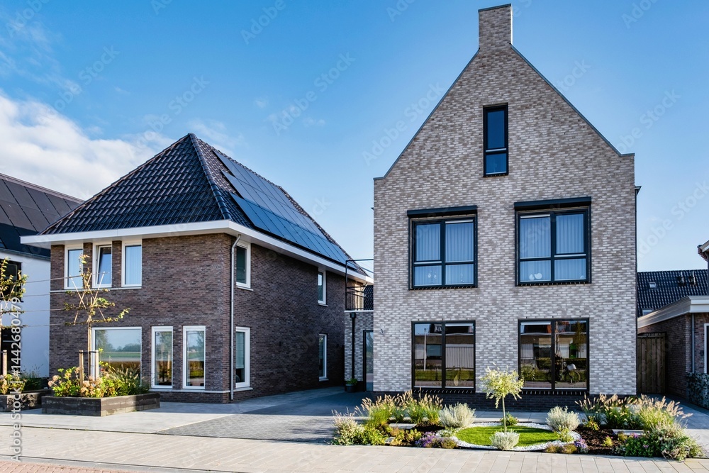 Modern houses featuring solar panels against a clear blue sky in a sustainable neighborhood Modern houses featuring solar panels against a clear blue sky in a sustainable neighborhood