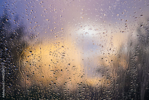 Purple rainy sunset through a foggy raindrop covered glass window with tree silhouettes