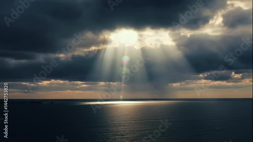 Sunbeams Break Through Dark Clouds Over Calm Ocean