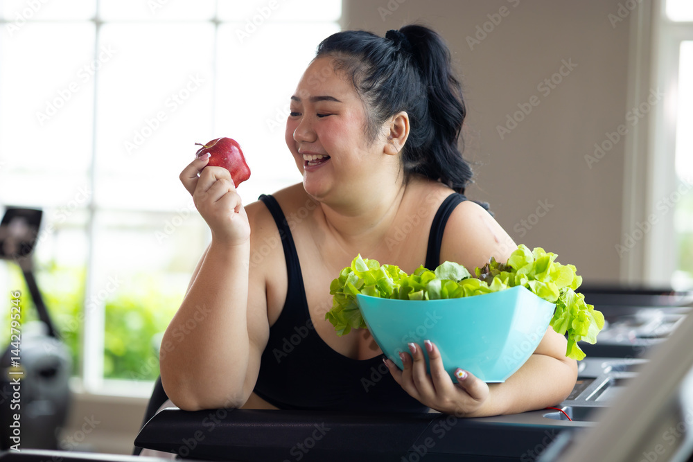 enjoying tasty vegetable salad. beautiful young chubby overweight woman wearing sporty fitness clothes doing exercise indoors at gym fitness sport club, body and health care