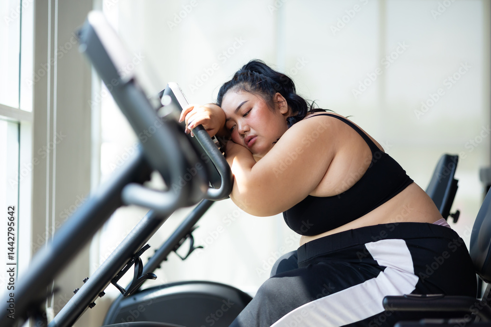 Tired fat asian woman on cycling. beautiful young chubby overweight woman wearing sporty fitness clothes doing exercise indoors at gym fitness sport club, body and health care