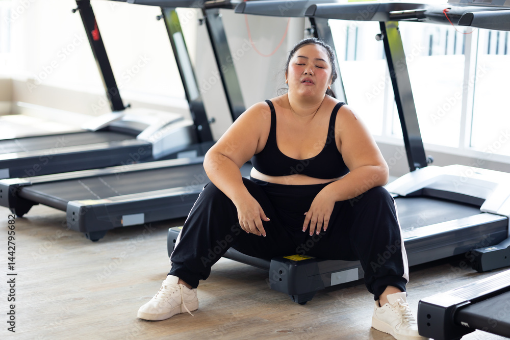 Tired fat asian woman. beautiful young chubby overweight woman wearing sporty fitness clothes doing exercise indoors at gym fitness sport club, body and health care