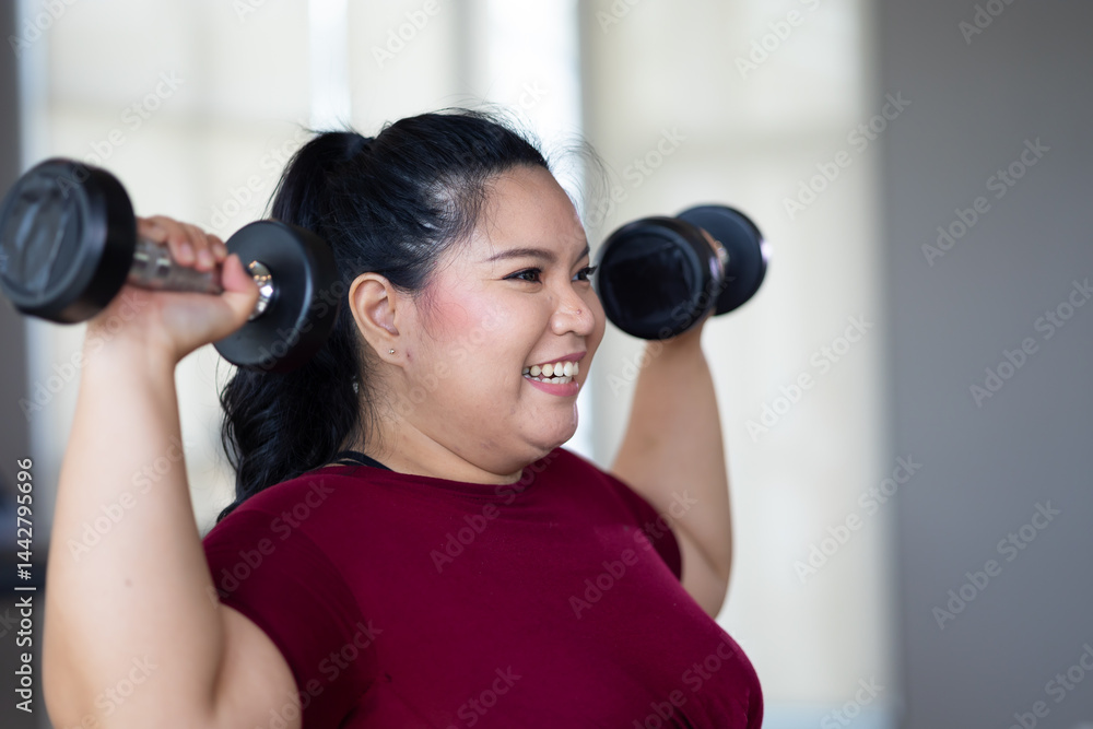 Young woman exercising with dumbbells. beautiful young chubby overweight woman wearing sporty fitness clothes doing exercise indoors at gym fitness sport club, body and health care