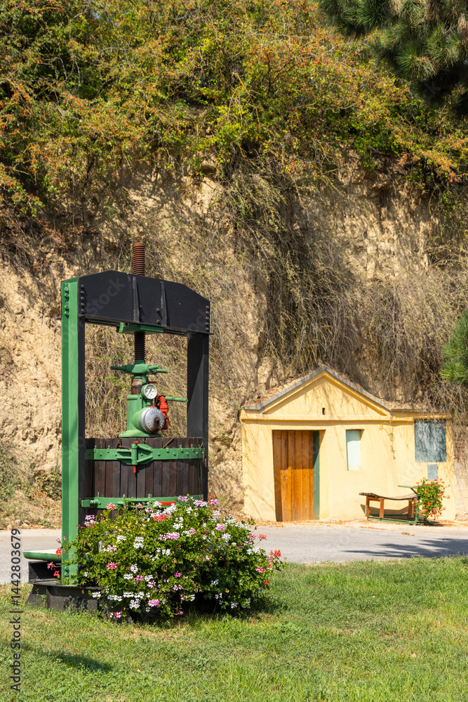 Traditional wooden wine press standing in front of a wine cellar entrance