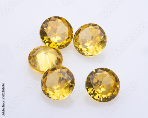 Obraz na płótnie Five round cut citrine gemstones are arranged on a white surface, showcasing their faceted brilliance and warm yellow hue in studio lighting w salonie