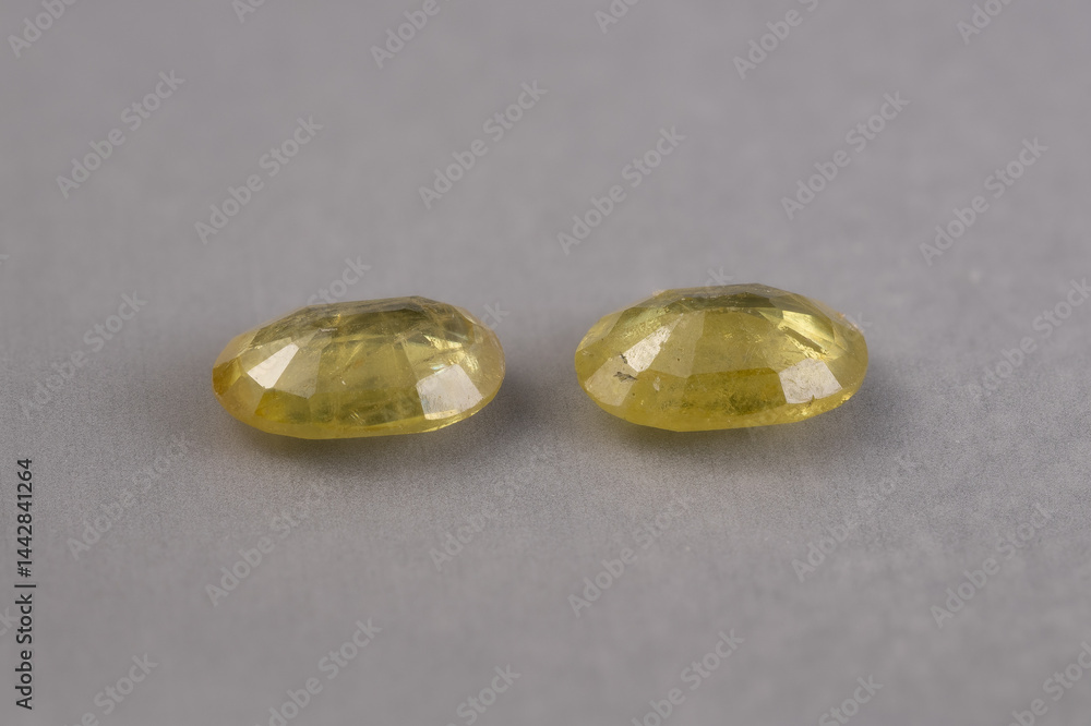 Two Natural Oval-Cut Yellow-Green Sphene Gemstones on Gray Background
