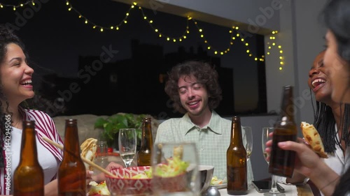 In a relaxed gathering of friends at dinner, young Latin man talks to women on a terrace