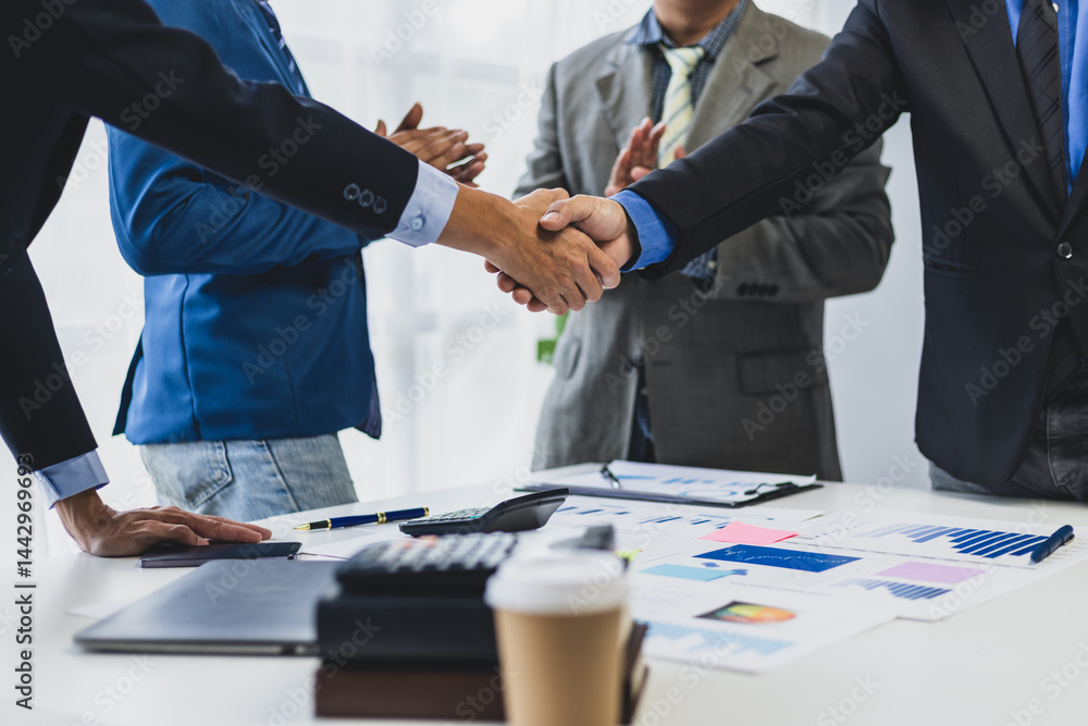 Business people shaking hands after successful meeting. Two business people shaking hands while their colleagues are clapping, after reaching an agreement during a productive meeting. Business people shaking hands after successful meeting. Two business people shaking hands while their colleagues are clapping, after reaching an agreement during a productive meeting.