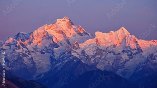 Panorama of snow covered mountain range glowing pink under alpenglow at twiligh