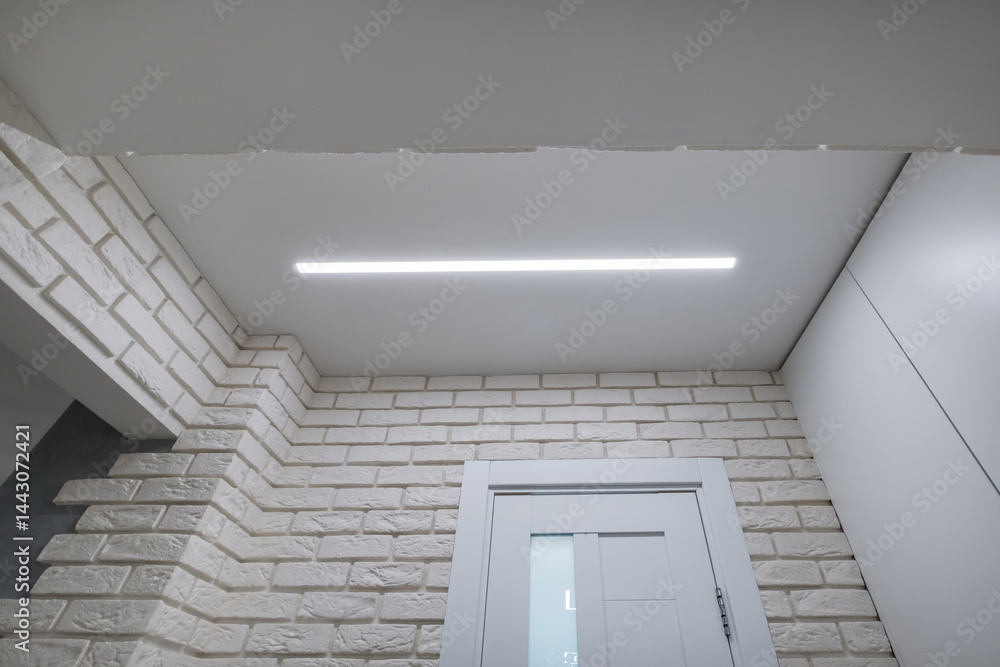 suspended ceiling with halogen spots lamps in form of squares and rectangles and drywall construction in empty room in apartment or house. Stretch ceiling white and complex shape.