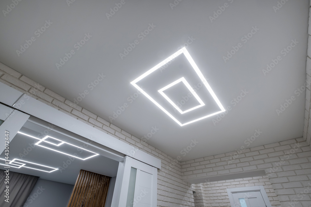 suspended ceiling with halogen spots lamps in form of squares and rectangles and drywall construction in empty room in apartment or house. Stretch ceiling white and complex shape.