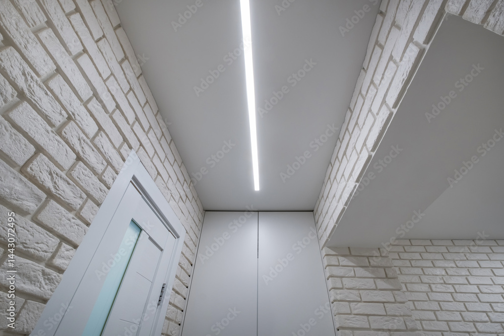 suspended ceiling with halogen spots lamps in form of squares and rectangles and drywall construction in empty room in apartment or house. Stretch ceiling white and complex shape.