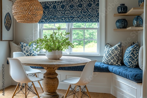  Small dining room design with round table, white chairs, blue fabric bench, and navy boho-patterned valance in a New England home.
