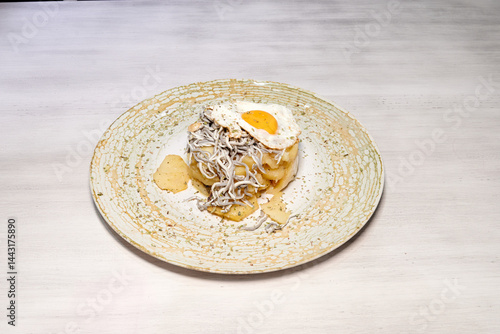 Obraz na płótnie A plate of food with a white egg on top. The plate is white and has a green design w salonie