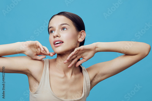 Young woman posing against a blue background, showcasing a fresh and natural beauty with a serene expression, perfect for wellness and lifestyle concepts
