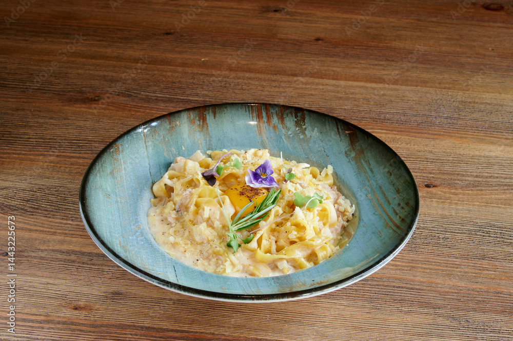 A bowl of pasta with a flower on top. The bowl is blue and the pasta is yellow