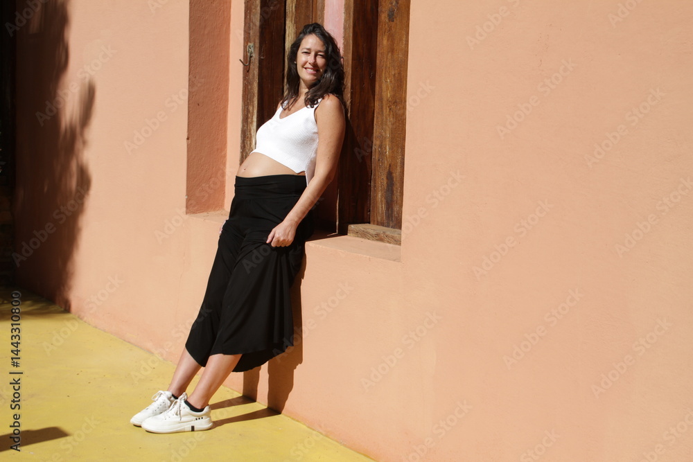 Fototapeta premium Pregnant women having sunbath at the wall of her house