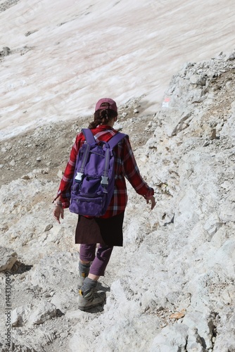 Obraz na płótnie Woman walking on stony path with backpack on shoulders and hiking boots on feet w salonie