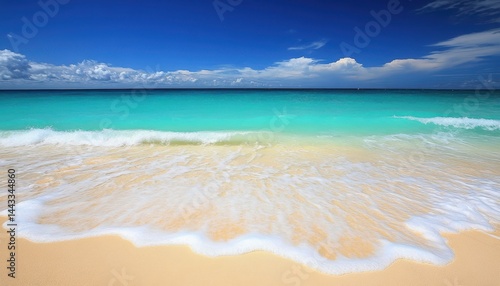 Tropical beach scene with turquoise water and white waves on golden sand.  Vast clear sky with fluffy clouds