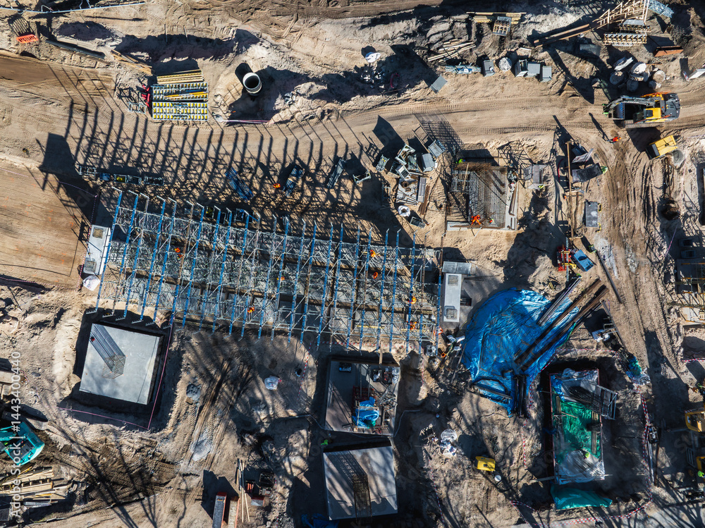 Aerial view of an active construction site in Riga, Latvia, featuring a steel framework, workers, machinery, and materials for the Southern Bridge project.