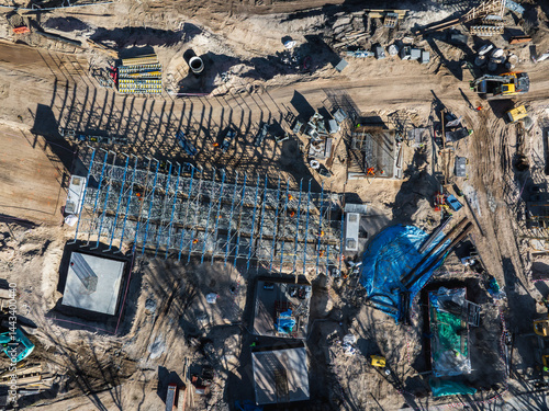 Aerial view of an active construction site in Riga, Latvia, featuring a steel framework, workers, machinery, and materials for the Southern Bridge project.
