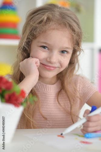 cute girl in the nursery draws at the table