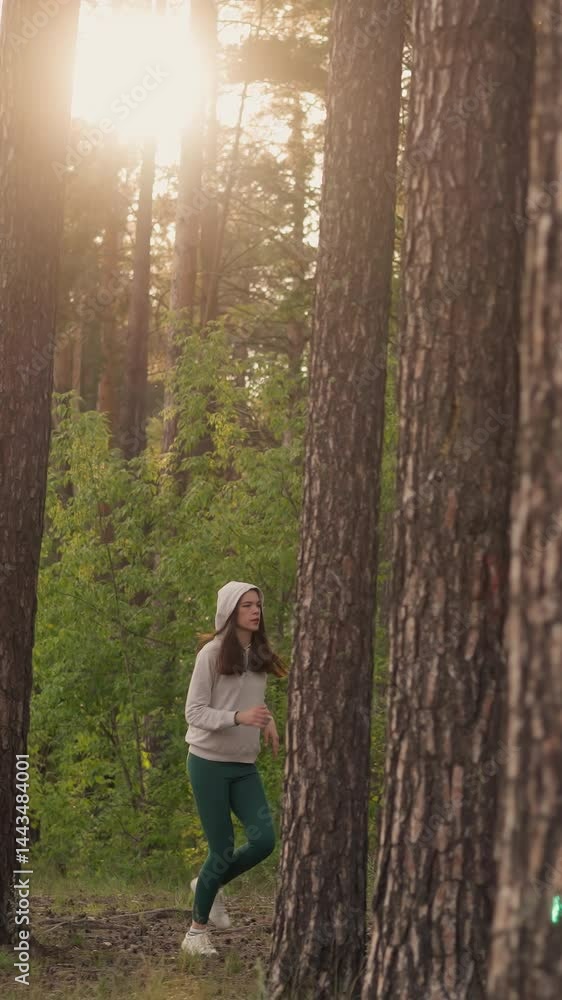 Female jogger runs along path in forest. Woman athlete engages in jog emphasizing cardio exercises as part of fitness training in nature at sunset Female jogger runs along path in forest. Woman athlete engages in jog emphasizing cardio exercises as part of fitness training in nature at sunset