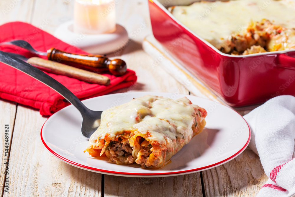 Cannellone with meat filling, tomato sauce and cheese on a light wooden table.