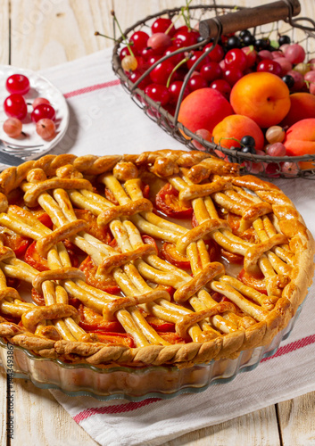 Obraz na płótnie Apricot pie decorated with dough ornament and a metal basket with fruits and berries. w salonie