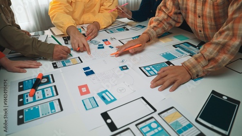 A vibrant workspace filled with professionals engaged in a collaborative design session. Hands draw and discuss mobile app prototypes and sketches, showcasing creativity and teamwork. SACTR