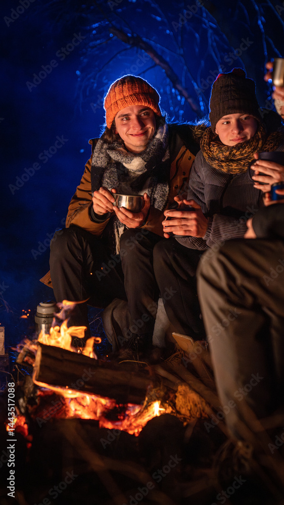 Obraz premium Friends sitting around a campfire in the woods on a winter evening