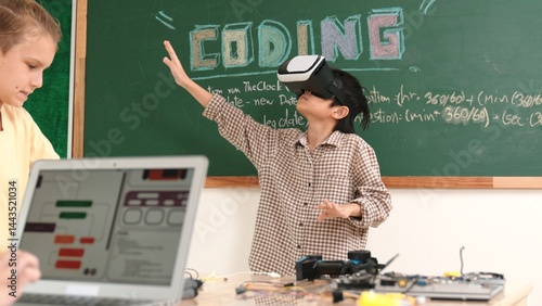 Obraz na płótnie Asian boy wearing VR headset to enter metaworld at table with board while girl coding system. Diverse student working together to develop program and writing engineering code. Pedagogy. w salonie