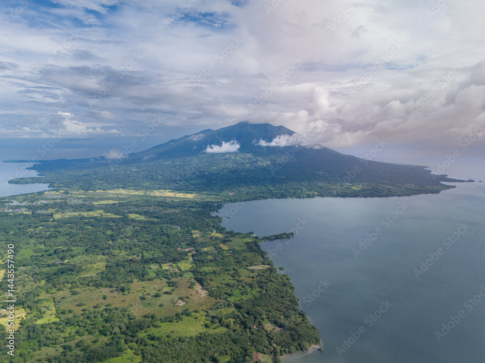 Aerial view of lush landscape featuring volcano near tranquil lake on a cloudy day