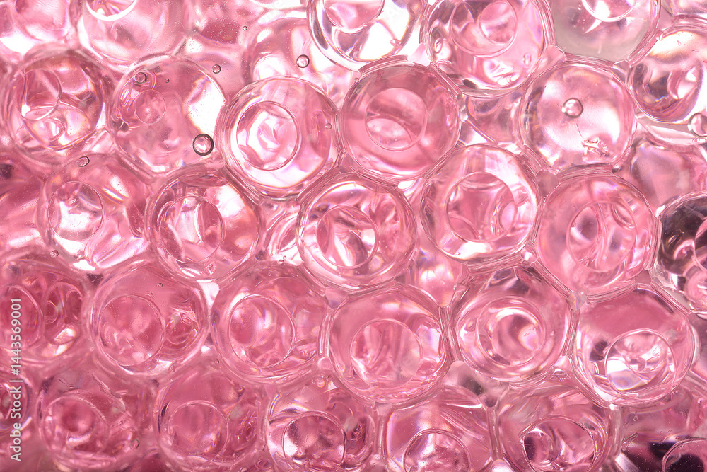 A macro close-up reveals a dense cluster of translucent pink gel beads, showing their round shapes and internal reflections