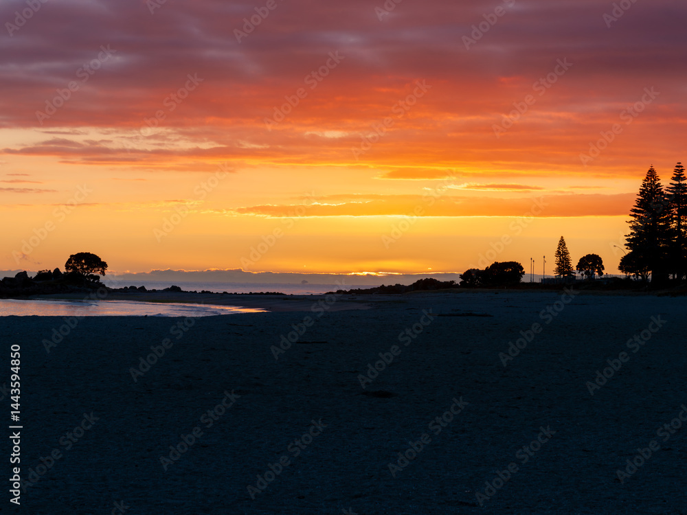 Intense sky sunrise colours along Mount Maunganui Main Beach