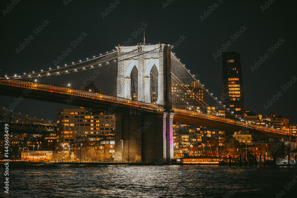 Fototapeta premium Brooklyn Bridge Illuminated at Night Over East River