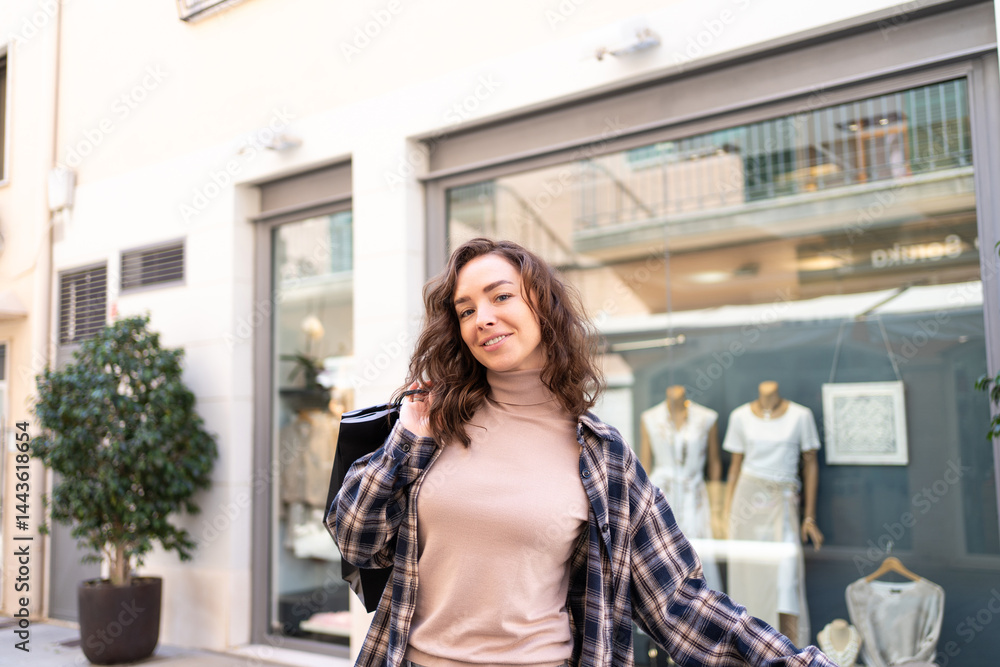 Fototapeta premium Stylish woman with shopping bags walking outside a fashion boutique, enjoying a shopping day in the city.