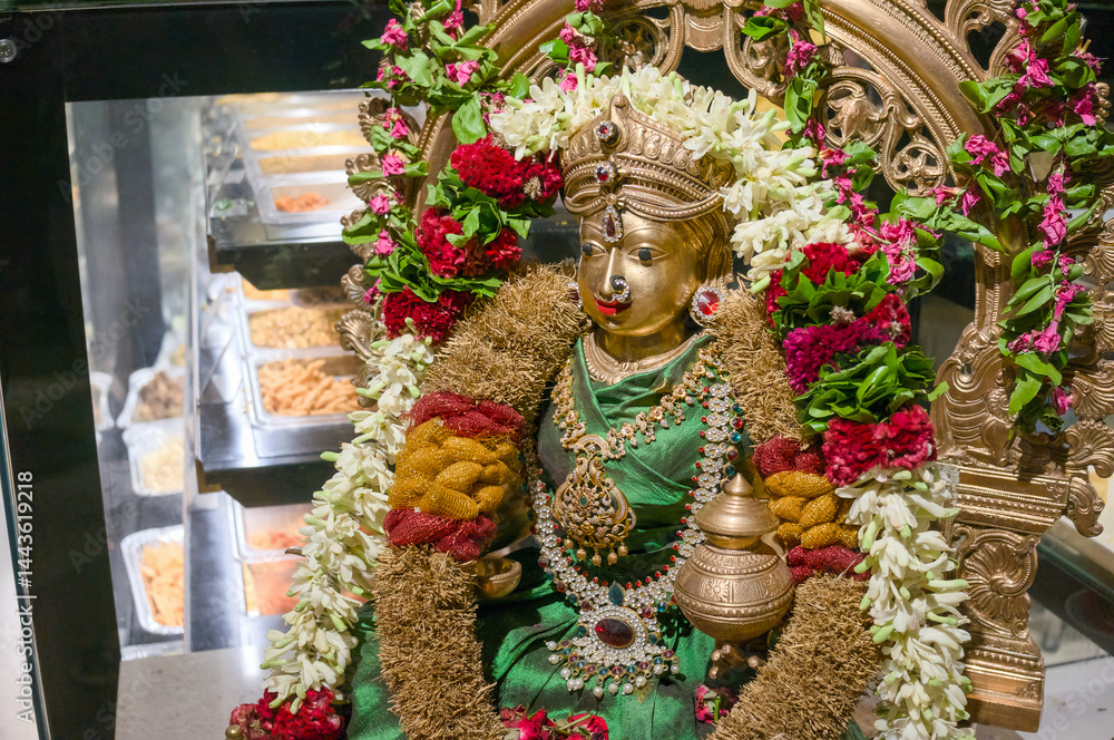 Fototapeta premium Goddess statue adorned with flowers in temple setting