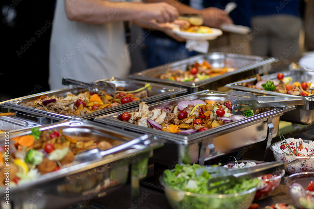 Obraz premium Catering buffet featuring assorted colorful vegetables and salads at a gathering with guests serving themselves