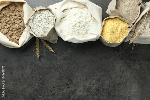 Obraz na płótnie Different types of flour in bags on grey table, flat lay. Space for text w salonie