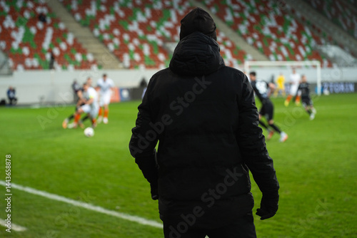 Obraz na płótnie Head coach's back and soccer match at the stadium in the background. w salonie