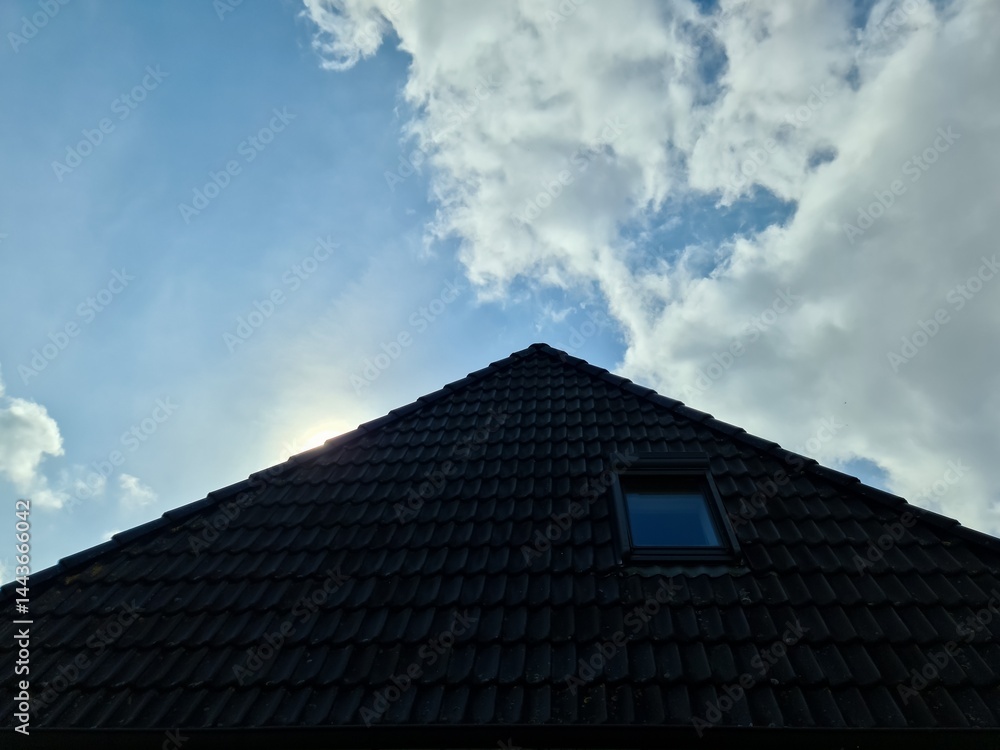 Dark pitched roof with skylight and sun shining through clouds Dark pitched roof with skylight and sun shining through clouds