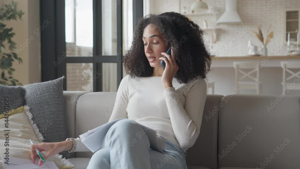 Woman On Phone Reviewing Documents, Gesturing While Discussing Work From Home Woman On Phone Reviewing Documents, Gesturing While Discussing Work From Home