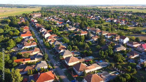 Aerial drone view of a peaceful rural village, traditional houses, red rooftops, and straight streets surrounded by lush greenery and open farmland. Eastern-European village. Balkan village. Hungary.