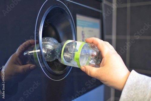 A woman hands over plastic bottles to a recycling machine.