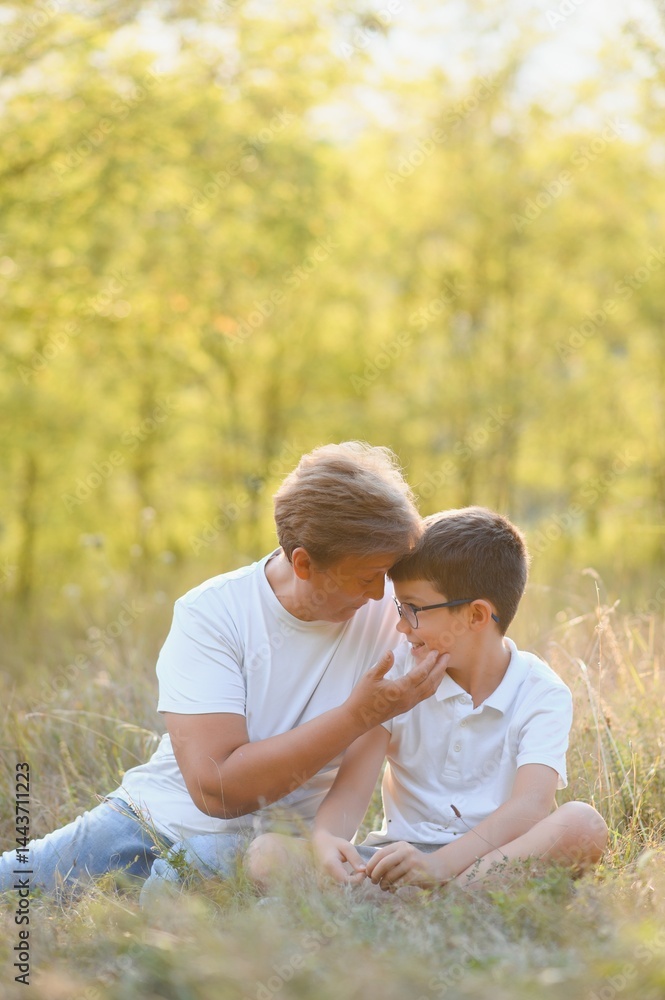 Fototapeta premium Grandmother walking with her grandson. Relaxing and joying in sunset