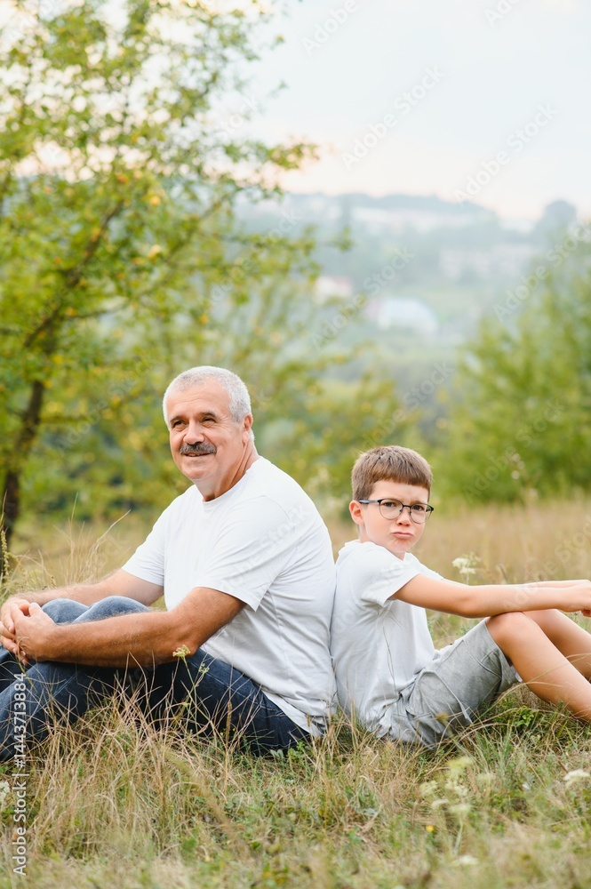 Fototapeta premium Grandfather and grandson walking at sunset