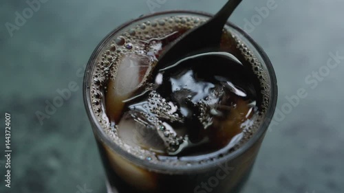 Closeup footage of stirring the ice cubes in an iced tea glass with a small spoon