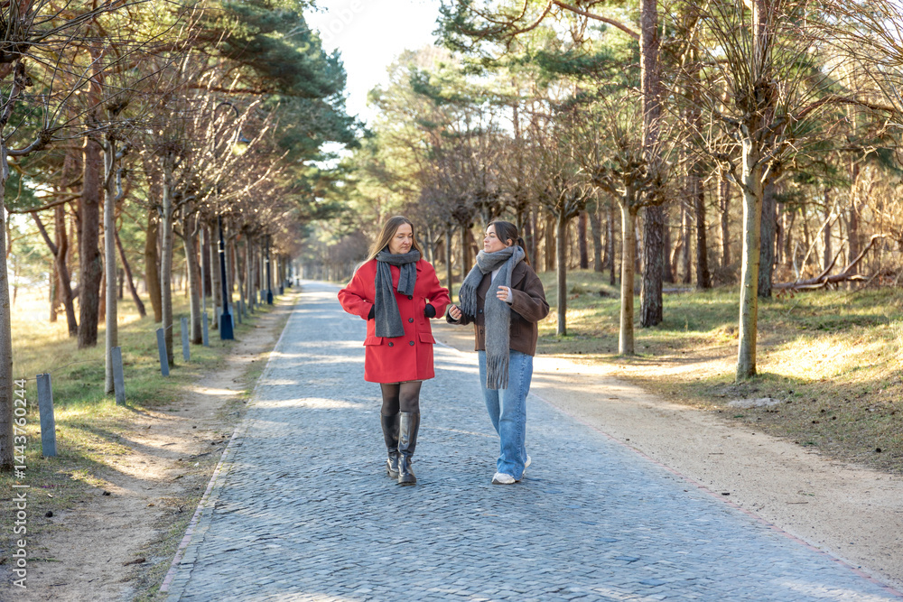 Fototapeta premium Two women walking in the park. Friends walking on a path in the park. Nature.